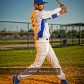 A baseball player wearing a white uniform swings his bat at the baseball