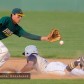 A baseball player slides into second base as the ball is caught