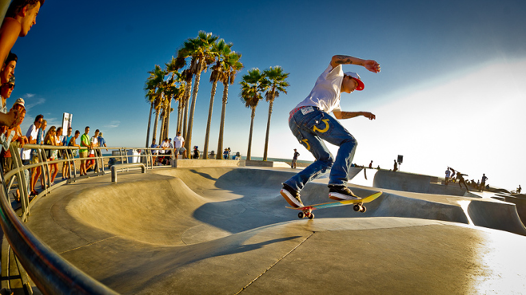 Skateboarder practicing his board skills at Venice Beach.   