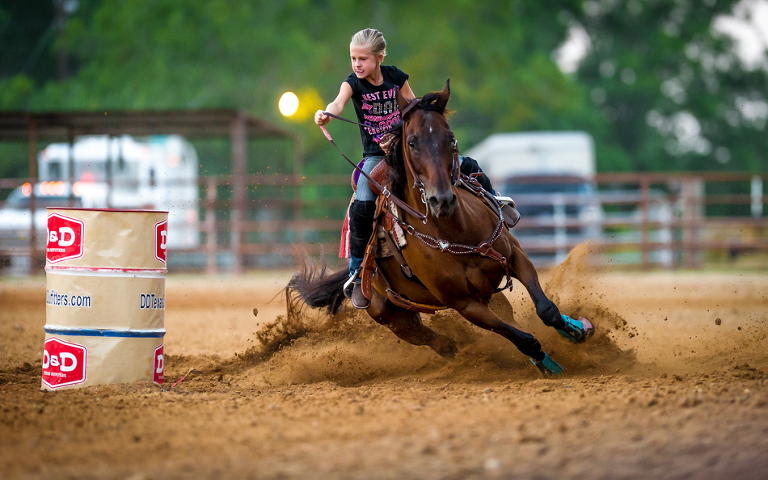 A young rider navigates her horse around a barrel during the Barrel Racing Series held at Rio Cibolo Ranch in Marion, Texas.  It takes a bond between a horse and rider to be successful in barrel racing.