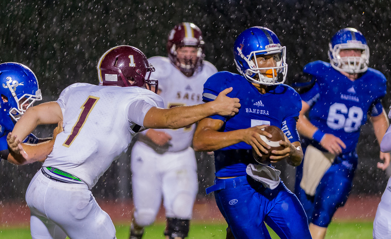 Bandera quarterback, Joe Rodriguez attempts to elude Andy Griffes of San Antonio Christian during a wet game in Bandera.  SACS went on to win the game 28 - 0.  Click here to see more photos.