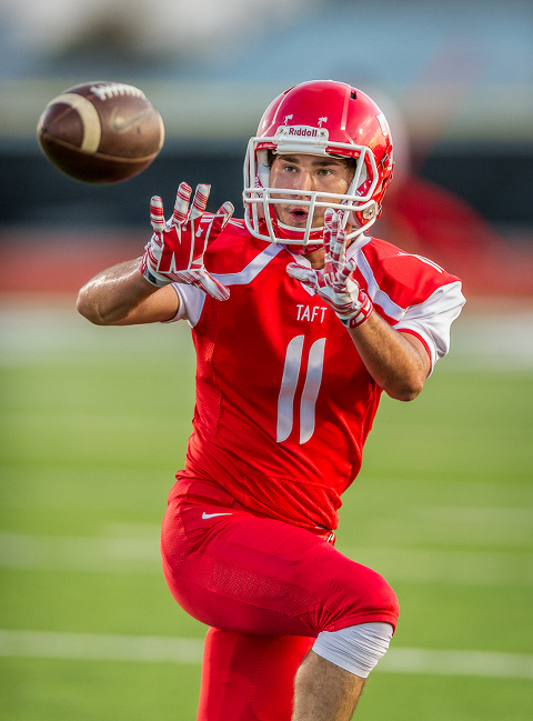 San Antonio Taft high school player warm up before a football game. For this image, I used a 400mm lens at f/2.8.  I like how the lens compresses the background and blurs it so your focus is entirely on the player.